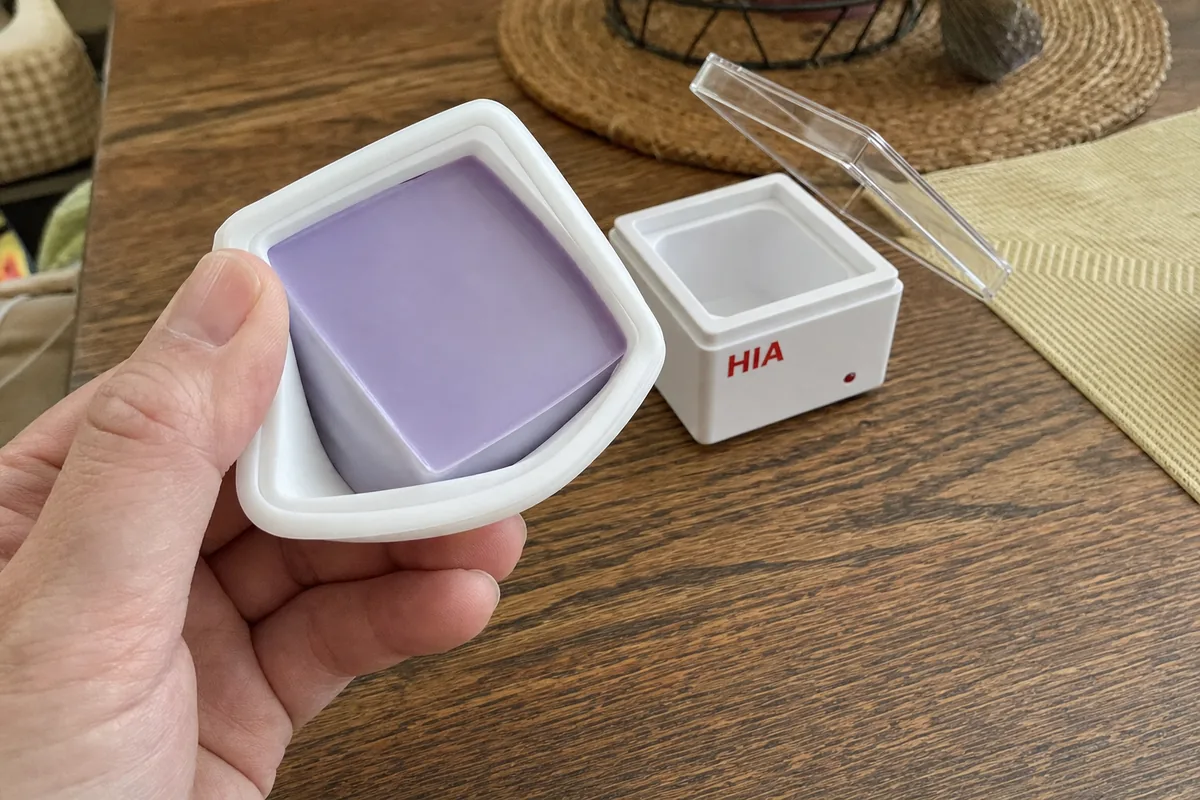 A hand flexing the silicone dish to pop out cooled wax